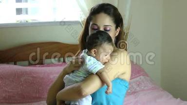 拉美裔拉丁裔母亲把<strong>流口水</strong>的婴儿抱在肩膀上，然后在背部轻敲，这样婴儿就可以打嗝了